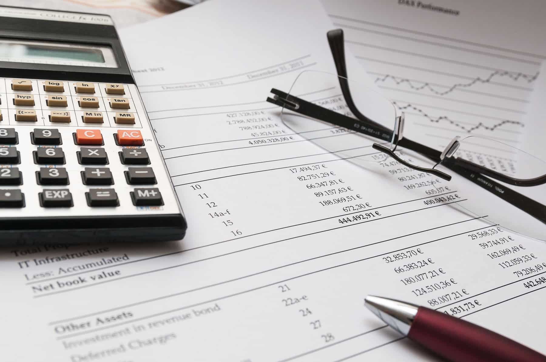 A calculator and pen on top of some papers